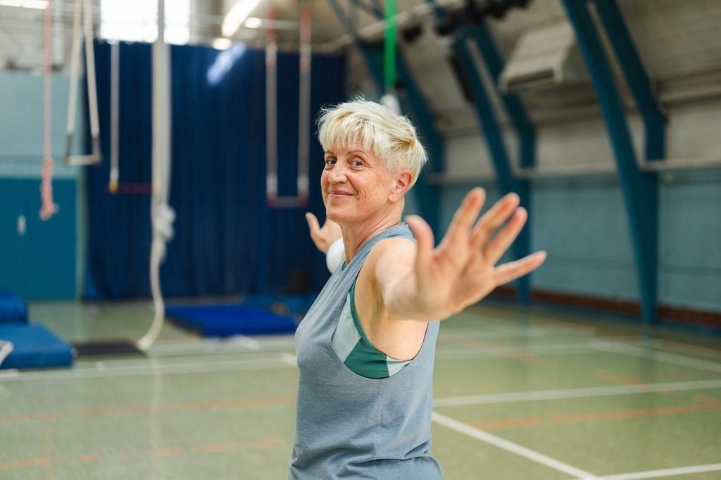 a woman with short blonde hair stretching in a gymnasium